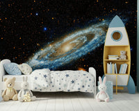 Andromeda mural of a glowing spiral galaxy behind a star-print kids bed and blue rocket bookshelf