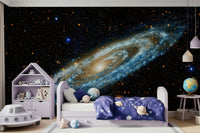 Andromeda galaxy mural in blue and gold above a lilac kids bed with planet bedding and a UFO toy