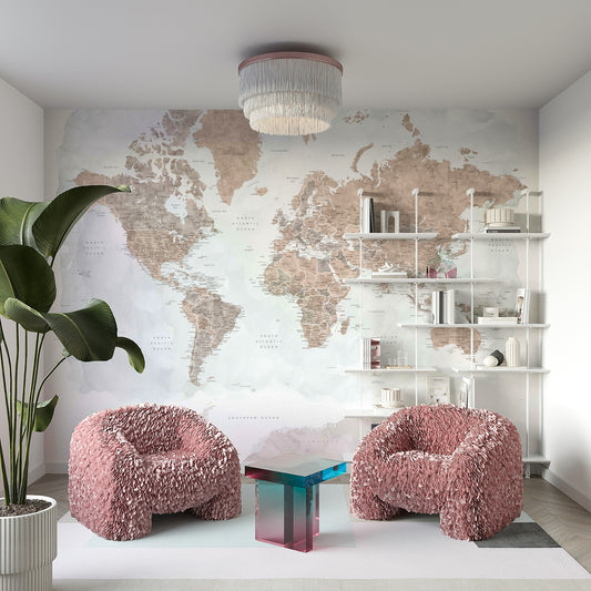 Antique World Map Watercolor wallpaper in sepia tones behind blush pink feathered armchairs and white shelves in a lounge