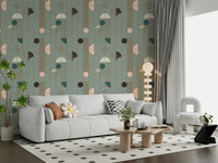 Art Deco Geometric Harmony wallpaper in green and blush deco pattern behind a grey sofa with daisy pillow and armchair
