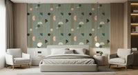Art Deco Geometric Harmony wallpaper in green deco shapes behind a grey bed with two cream armchairs and globe lamps