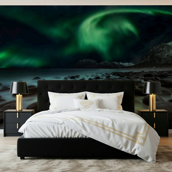 Mystic Shore Lights wallpaper mural of a green aurora over a rocky shore above a black bed in a bedroom
