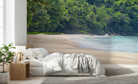 Beach Haven wall mural of a secluded beach and lush jungle behind a white bed and wood nightstand in a bedroom