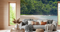 Beach Haven wall mural of sand and turquoise surf behind a grey sofa piled with boho pillows in a living room