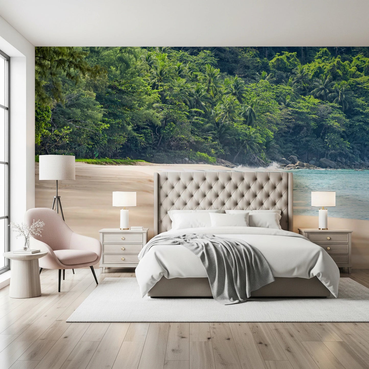 Beach Haven wall mural of a sandy cove and jungle behind a cream tufted bed and pink armchair in a bedroom