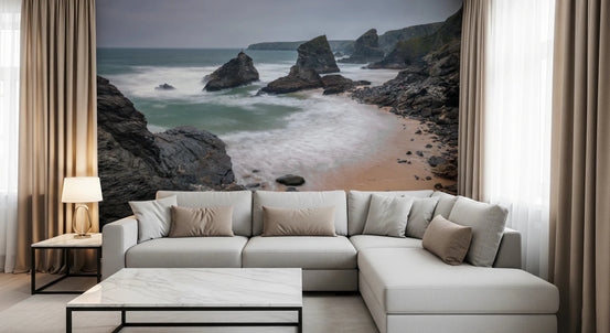 Bedruthan Steps Beach Cornwall wall mural of rocky sea stacks and surf behind a cream sectional sofa in a living room