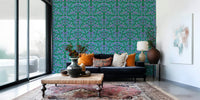 Berry Branch Symphony wallpaper behind a navy sofa with orange cushions and a vintage pink rug