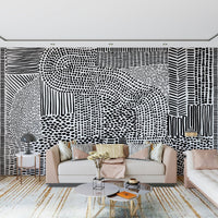 Black And White Maze wallpaper mural behind a blush pink sofa with gold accents in a living room