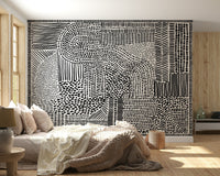 Black And White Maze wallpaper mural behind a cream bed with a knit throw and wood walls