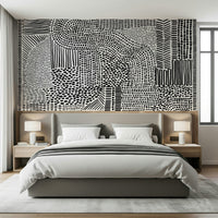 Black And White Maze wallpaper mural behind a gray upholstered bed with twin lamps in a bedroom