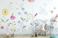 Bloom and Bird wallpaper mural of painted wildflowers behind a wooden toy pram and bunny chair in a kids room