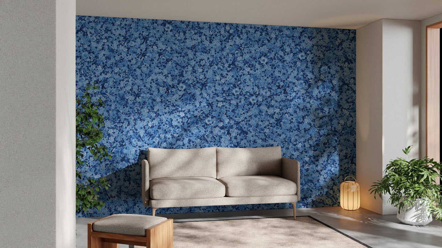 Blue Bird Flower wallpaper mural of blue blossoms behind a cream loveseat and green plants in a living room