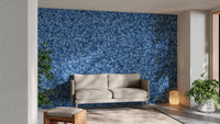 Blue Bird Flower wallpaper mural of blue blossoms behind a cream loveseat and green plants in a living room