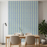 Blue Bloom Stripes wallpaper mural in a dining room behind a wood table and beige chairs, blue and yellow florals