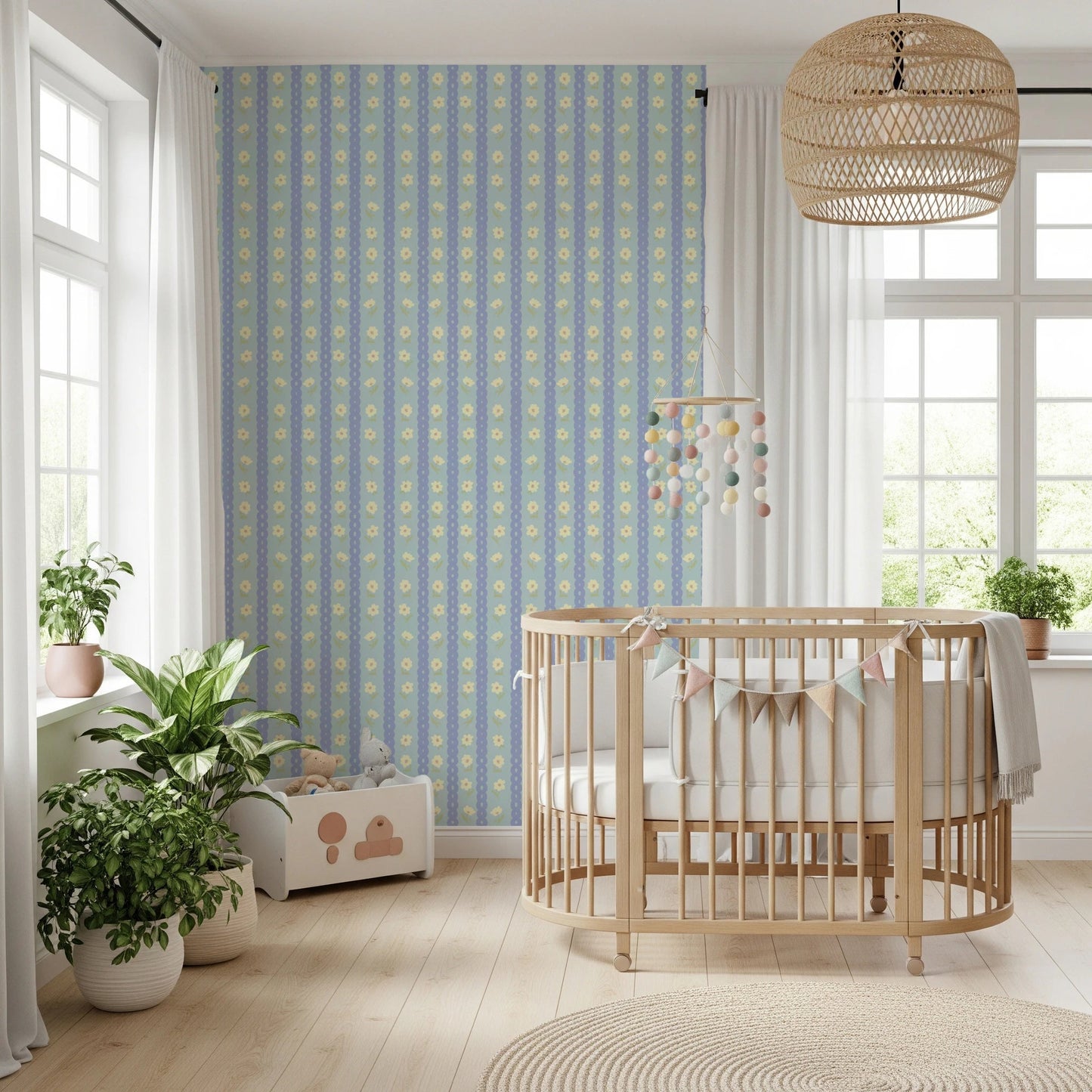 Blue Bloom Stripes wallpaper mural in a nursery behind a wood crib with pompom mobile and leafy plants