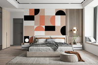 Blush Geometry wallpaper mural behind an upholstered bed with grey throw and a round globe table lamp