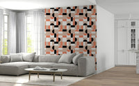 Blush Geometry wallpaper in blush and black accenting a wall above a grey sectional sofa in a living room