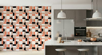 Blush Geometry wallpaper in coral and black on a kitchen wall beside grey cabinets and a marble island