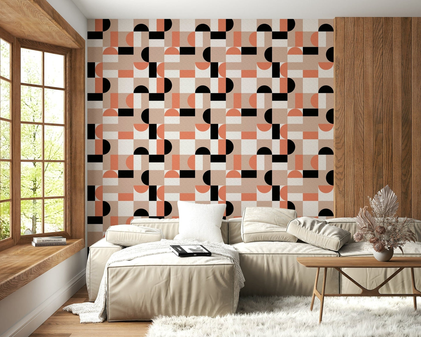 Blush Geometry wallpaper in coral and black on a wood-accent wall behind a beige sectional sofa in a living room