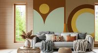 Boho Sun and Moon wallpaper mural in rust and sage behind a grey sofa with chunky knit throws in a sunny living room