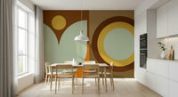 Boho Sun and Moon wallpaper mural with rust circles and sage shapes in a dining room with wood chairs and white cabinets