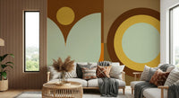 Boho Sun and Moon wallpaper mural with brown and sage shapes behind a cream sofa with boho pillows by a wood-slat wall
