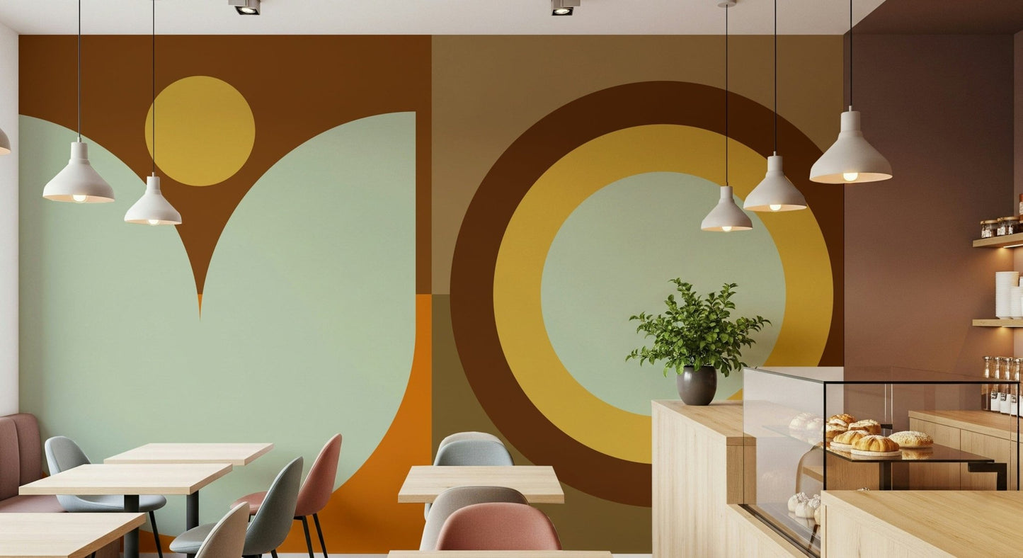 Boho Sun and Moon wallpaper mural in rust, yellow and sage on a cafe wall with pendant lights and a wood pastry counter
