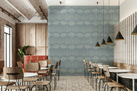 Boho Waves On Arona Canvas wallpaper as a dusty blue feature wall in a cafe with wood chairs and black cone pendants