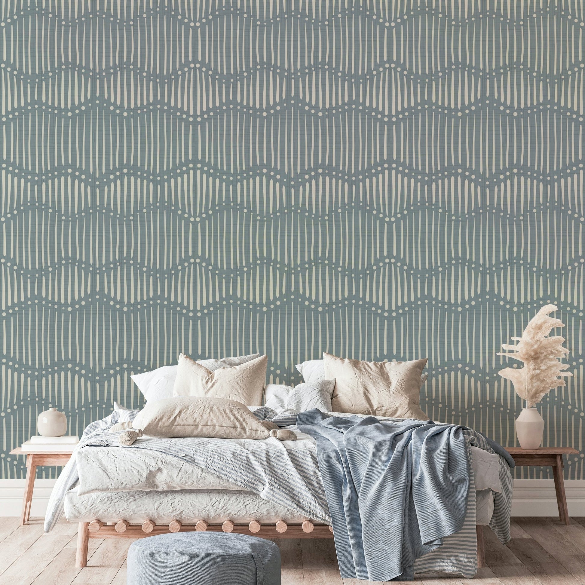 Boho Waves On Arona Canvas wallpaper in slate blue behind a wood platform bed with beige bedding and pampas grass