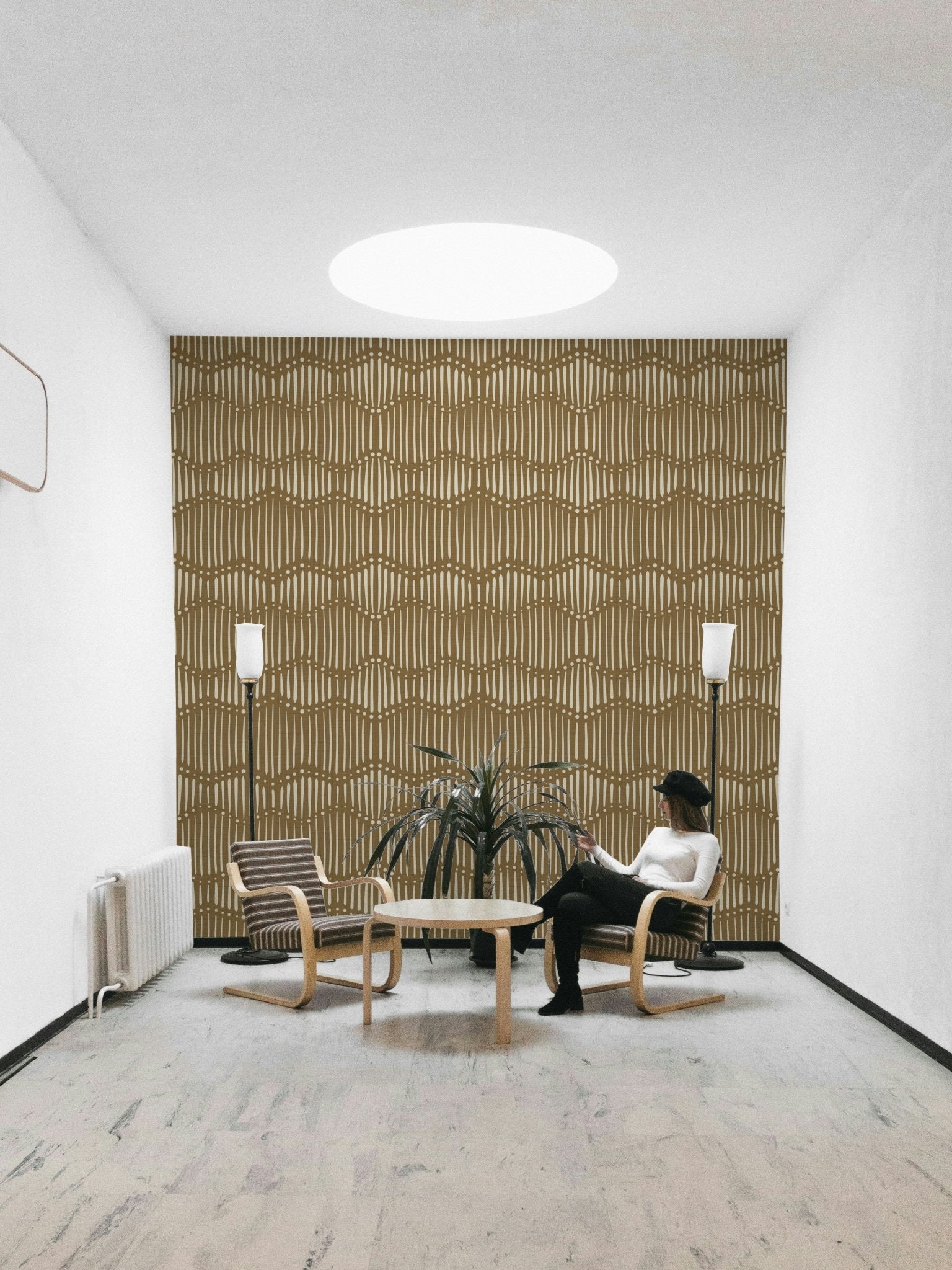 The mural is installed in a calm, bohemian living room behind a simple, light-colored sofa.

