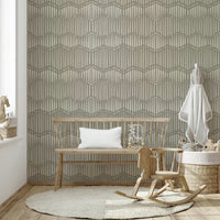 The mural is installed in a calm, bohemian living room behind a simple, light-colored sofa.

