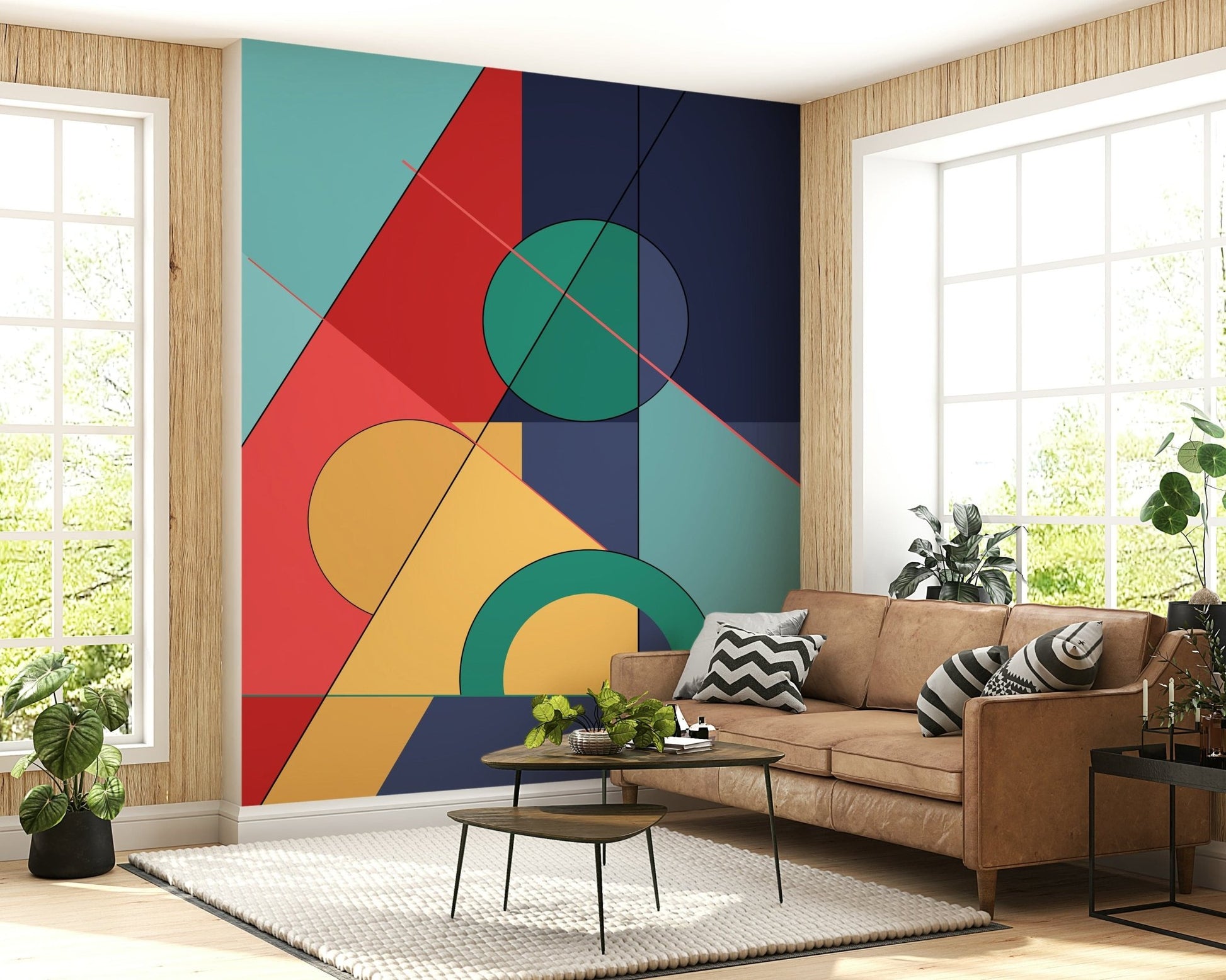Bold Bauhaus wallpaper mural of bold geometric shapes behind a tan leather sofa with chevron pillows