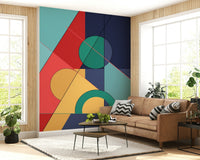 Bold Bauhaus wallpaper mural of bold geometric shapes behind a tan leather sofa with chevron pillows