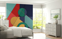 Bold Bauhaus wallpaper mural of red and navy geometric shapes above a white bed and dresser