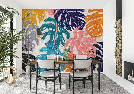 Colorful Bold Monstera Leaves wallpaper mural behind a wood dining table and grey chairs in a dining room