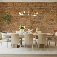 Brickwork Beauty wallpaper mural in warm tan stone behind a long beige dining table and gold chandelier