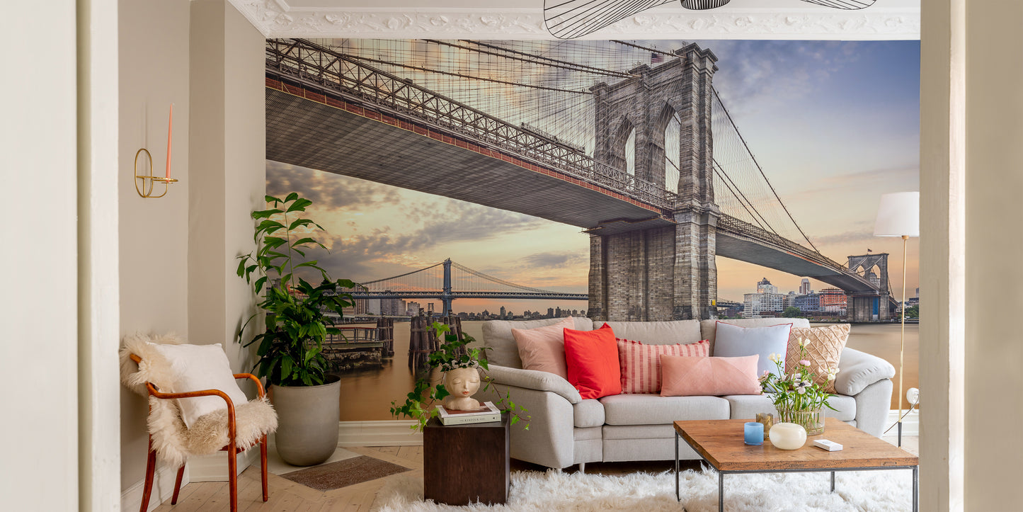 Brooklyn Bridge New York City wallpaper mural at sunset behind a gray sofa with coral pillows in a living room