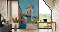 Brooklyn Bridge Vista wallpaper mural with the bridge and brick building behind a wood desk and laptop in a home office