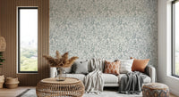 Butterfly Bloom Line Art wallpaper above a grey sofa with rust cushions beside a wood-slat wall
