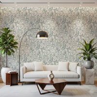 Butterfly Bloom Line Art wallpaper in teal roses behind a cream sofa with arc lamp and leafy plants