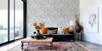Butterfly Bloom Line Art wallpaper with roses and butterflies behind a navy sofa and orange cushions
