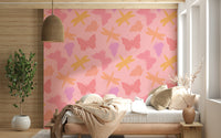 Butterfly and dragonfly wallpaper featuring warm yellow, pink, and purple motifs on a blush background.