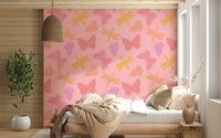 Butterfly and dragonfly wallpaper featuring warm yellow, pink, and purple motifs on a blush background.