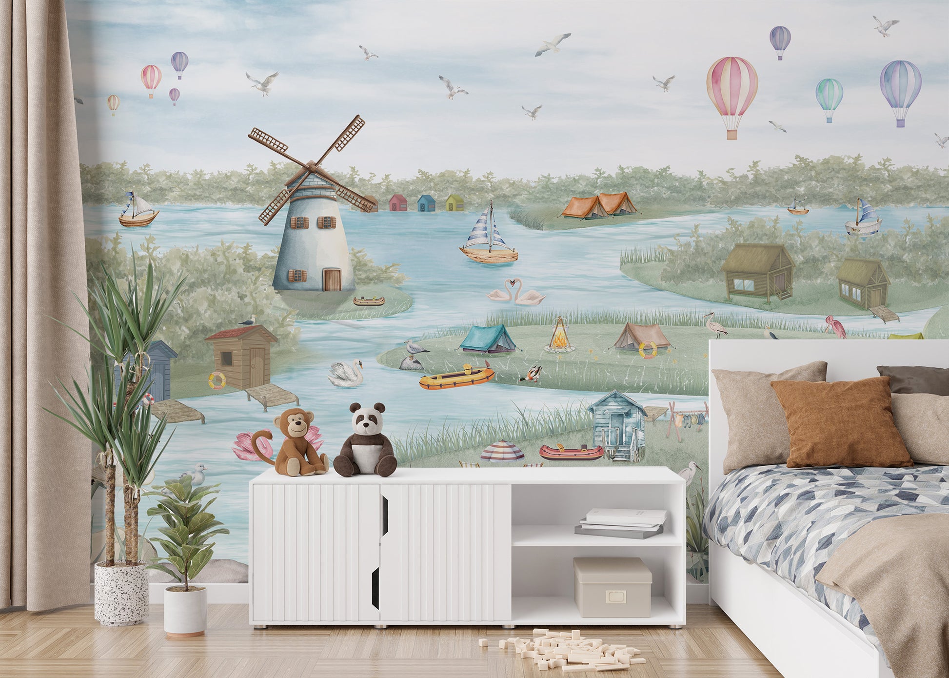 Breezy Shores wallpaper mural of a lakeside windmill beside a white bed and a sideboard with monkey and panda plush toys