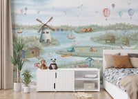 Breezy Shores wallpaper mural of a lakeside windmill beside a white bed and a sideboard with monkey and panda plush toys