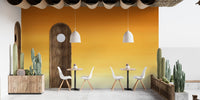 Honey Ombre wallpaper mural in sunset orange on a cafe patio with a wood arched door and potted cacti