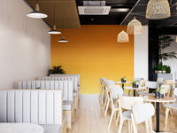 Honey Ombre wallpaper mural in golden tones behind white booths and wood cafe tables with rattan lights