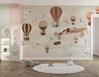 Whimsical Sky High Adventure wallpaper mural of hot air balloons, an elephant and vintage plane in a kids nursery with knit rug and toys