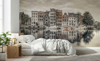 Canal Harmony wallpaper mural of sepia gabled houses along a canal behind white bedding and a wood nightstand in a bedroom