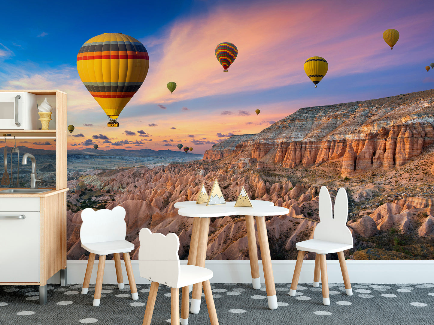 Cappadocia Balloons Sunset wallpaper mural in a kids room with a play kitchen and white bear chairs on a dotted rug